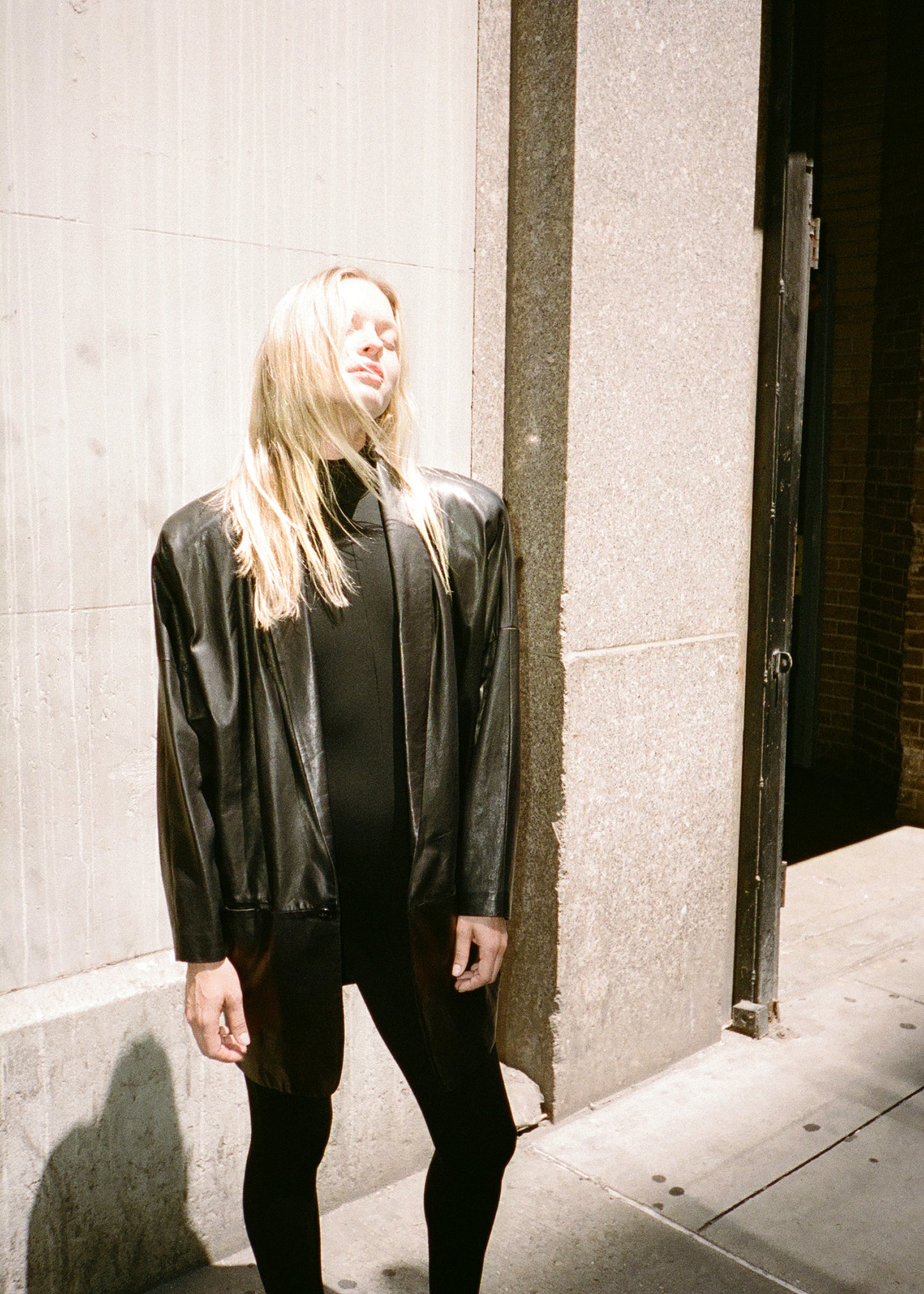 Fashion model wearing black leather jacket over one piece black bodysuit